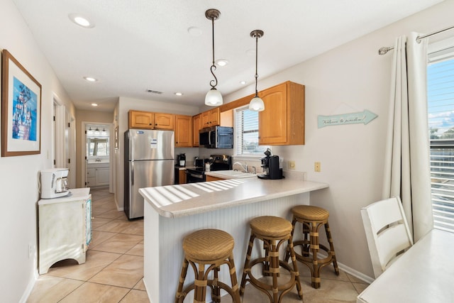 kitchen featuring light countertops, electric range oven, a kitchen breakfast bar, a peninsula, and freestanding refrigerator