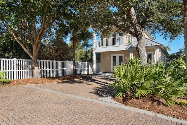 view of front of home with french doors, a fenced front yard, and a balcony