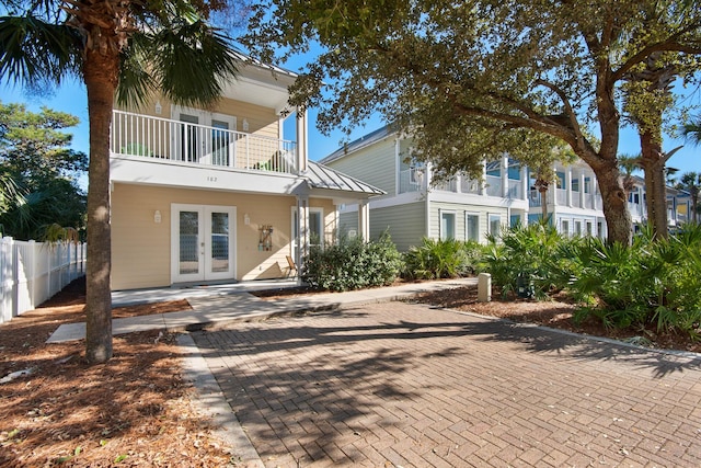 view of front of house featuring a balcony, fence, and french doors