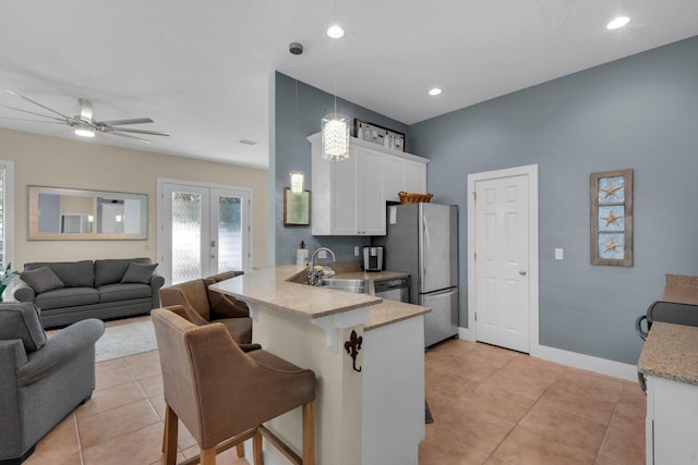 kitchen with a breakfast bar, french doors, stainless steel appliances, white cabinets, and a peninsula