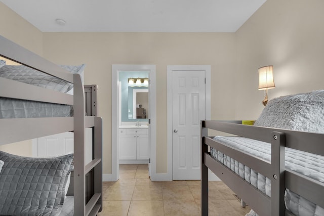 bedroom featuring light tile patterned flooring, a sink, and baseboards