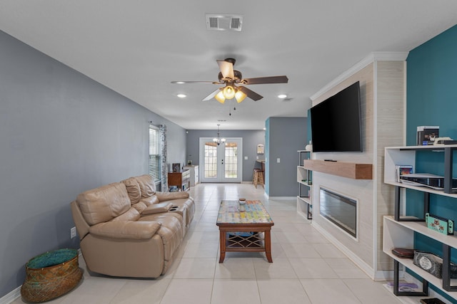 living room featuring a fireplace, visible vents, light tile patterned flooring, baseboards, and ceiling fan with notable chandelier