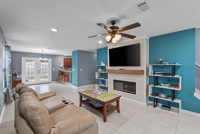 living area with light tile patterned floors, ceiling fan, visible vents, baseboards, and a glass covered fireplace