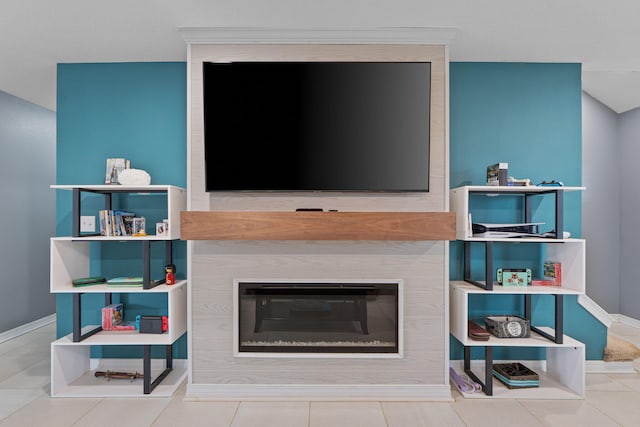 tiled living room featuring a large fireplace and baseboards