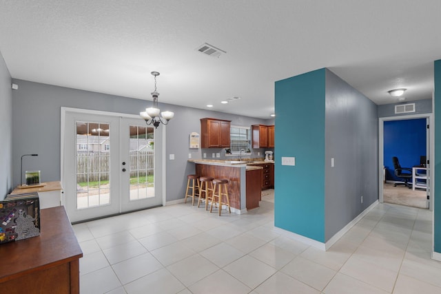 interior space featuring light tile patterned floors, visible vents, a kitchen breakfast bar, a peninsula, and french doors