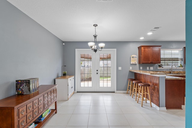 doorway to outside with light tile patterned floors, visible vents, an inviting chandelier, french doors, and a sink