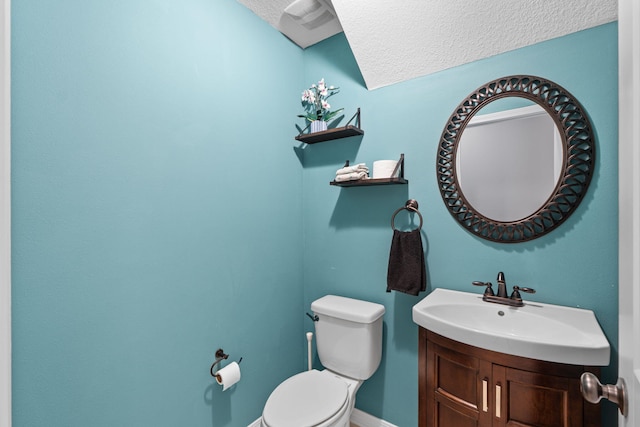 bathroom with a textured ceiling, vanity, and toilet