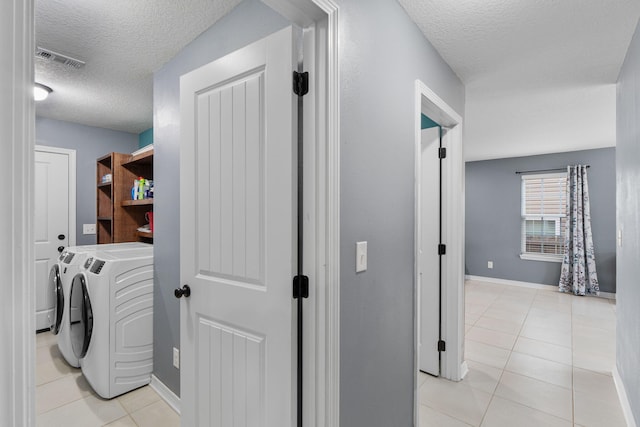 washroom featuring laundry area, light tile patterned floors, visible vents, washing machine and clothes dryer, and a textured ceiling