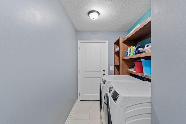 laundry area featuring light tile patterned floors, a textured ceiling, laundry area, baseboards, and washer and dryer