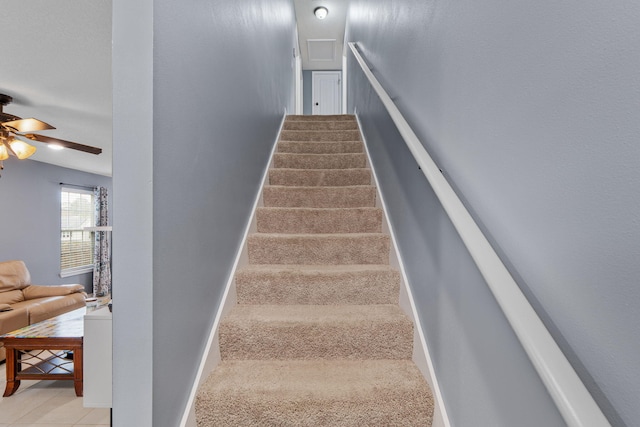 stairway with ceiling fan and baseboards