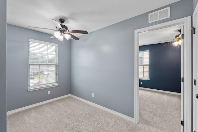 empty room with a ceiling fan, carpet, visible vents, and baseboards