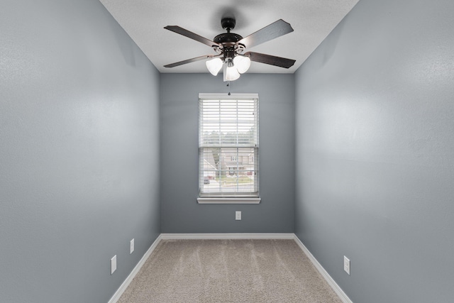 empty room with carpet floors, a ceiling fan, and baseboards