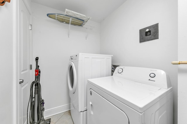 washroom featuring laundry area, baseboards, washer and clothes dryer, and light tile patterned flooring