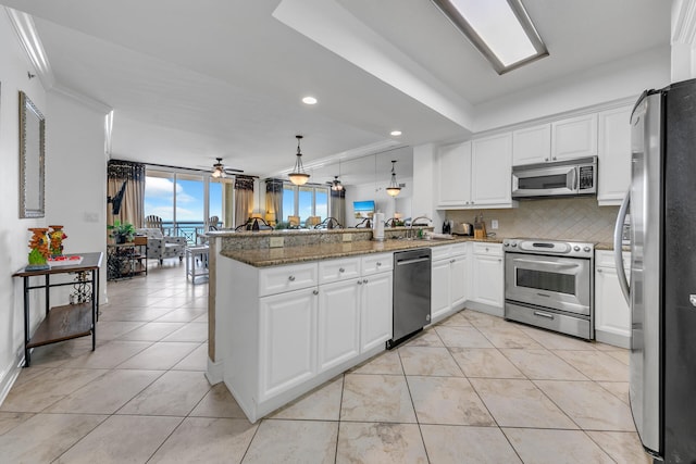 kitchen with light tile patterned floors, a peninsula, a ceiling fan, appliances with stainless steel finishes, and decorative backsplash