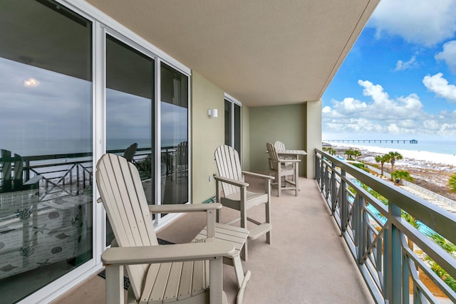 balcony featuring a view of the beach and a water view