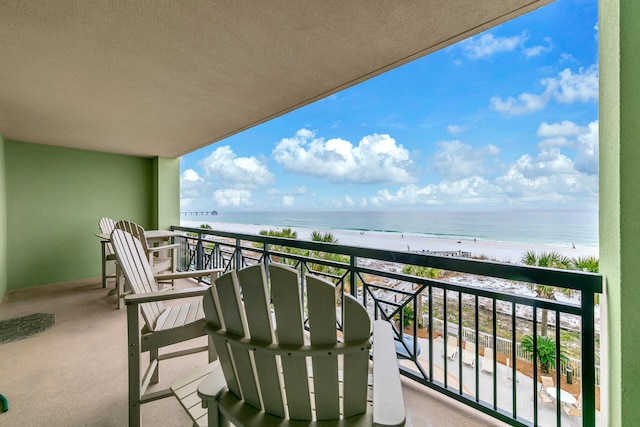 balcony with a water view and a view of the beach