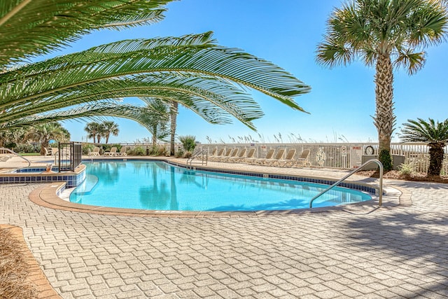 community pool featuring a patio area, fence, and a community hot tub