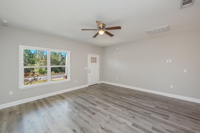 spare room featuring a ceiling fan, visible vents, baseboards, and wood finished floors