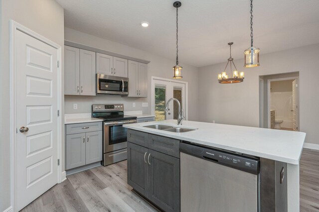 kitchen featuring light wood-type flooring, stainless steel appliances, a sink, and gray cabinetry