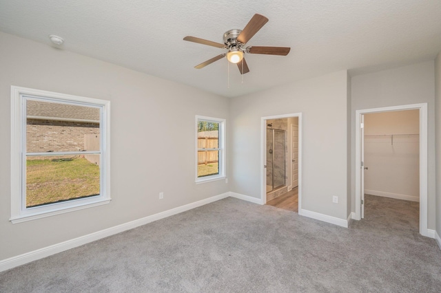 unfurnished bedroom featuring baseboards, ensuite bath, carpet, a spacious closet, and a closet