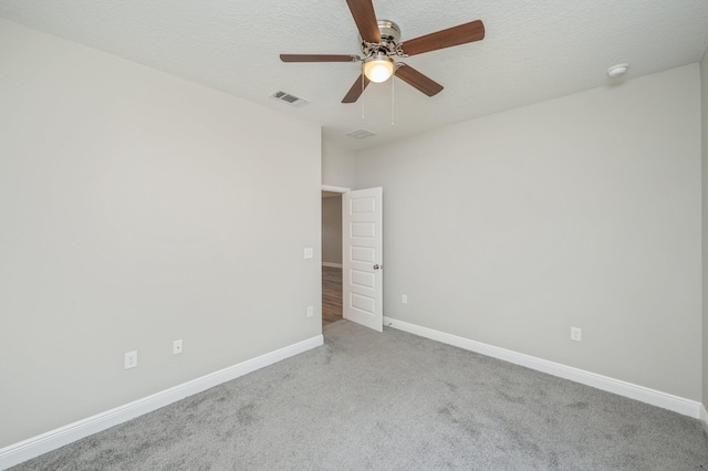 carpeted empty room with a textured ceiling, a ceiling fan, visible vents, and baseboards