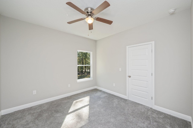 carpeted empty room featuring baseboards and a ceiling fan