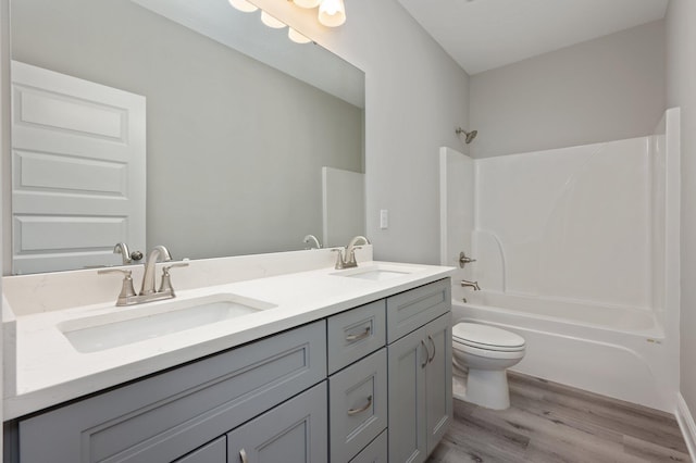 bathroom featuring shower / tub combination, a sink, toilet, and wood finished floors