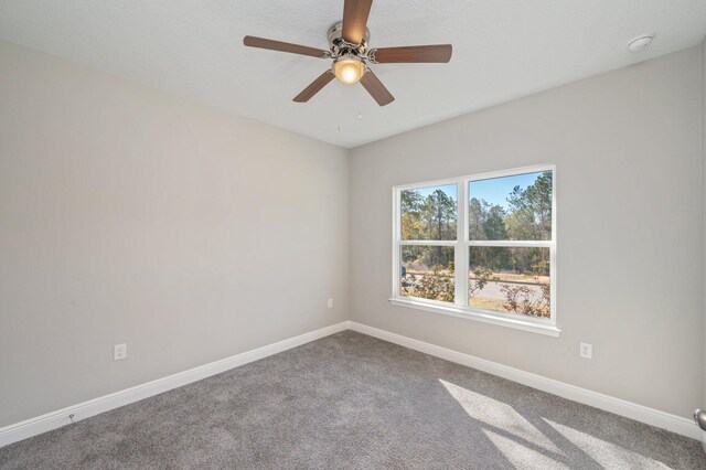 carpeted empty room featuring baseboards and a ceiling fan