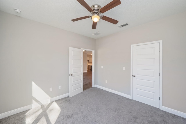 unfurnished bedroom with ceiling fan, a textured ceiling, visible vents, baseboards, and carpet