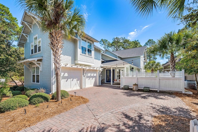 view of front of property featuring a garage, decorative driveway, and fence