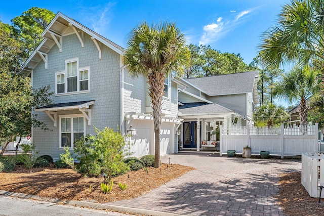 view of front of house with decorative driveway, fence, and an attached garage