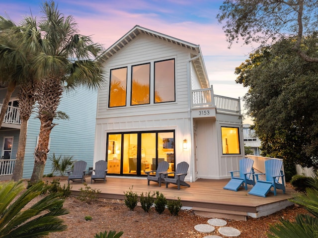 back of property at dusk featuring board and batten siding and a balcony