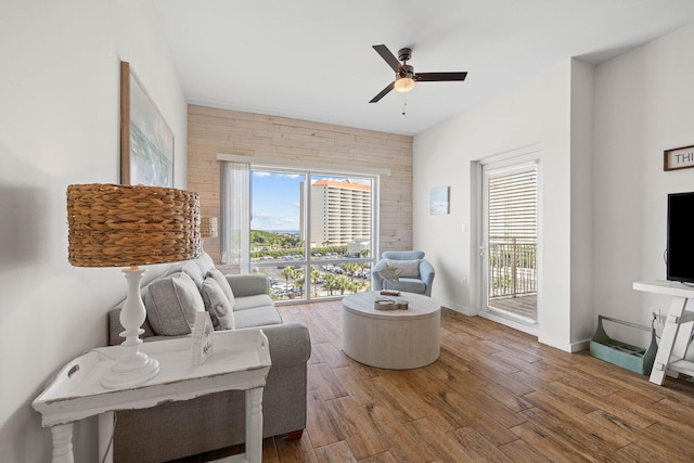 living area with baseboards, a ceiling fan, and wood finished floors