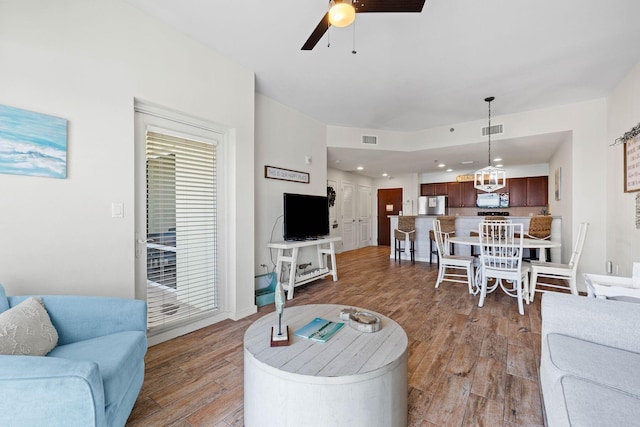 living room with recessed lighting, visible vents, light wood finished floors, and ceiling fan with notable chandelier