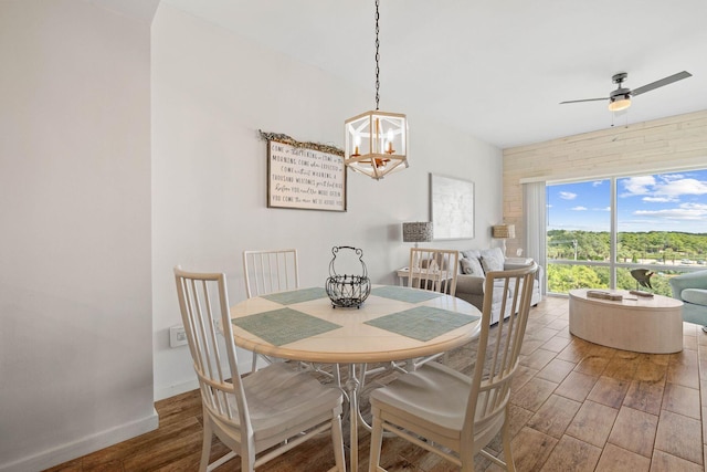 dining room featuring baseboards, wood finished floors, and ceiling fan with notable chandelier