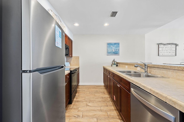 kitchen featuring recessed lighting, a sink, visible vents, wood tiled floor, and black appliances