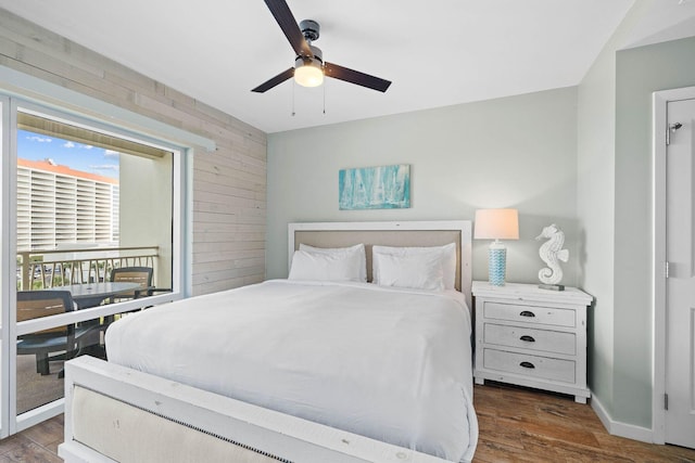 bedroom featuring baseboards, wood finished floors, a ceiling fan, and wooden walls