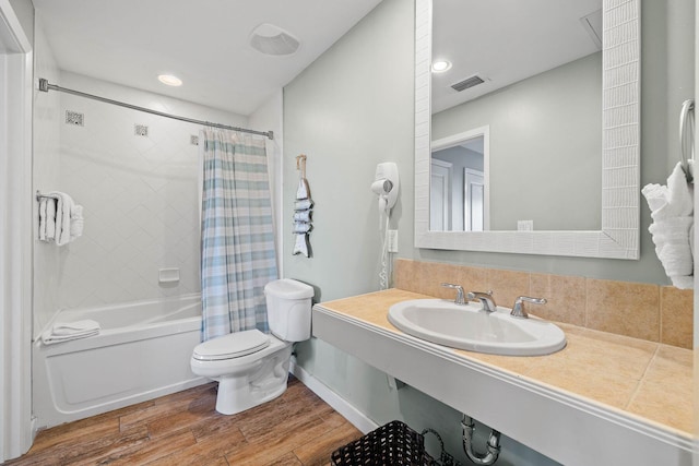 bathroom with shower / tub combo with curtain, visible vents, toilet, vanity, and wood finished floors