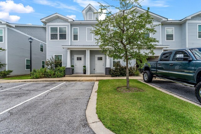 view of property featuring uncovered parking and a front yard