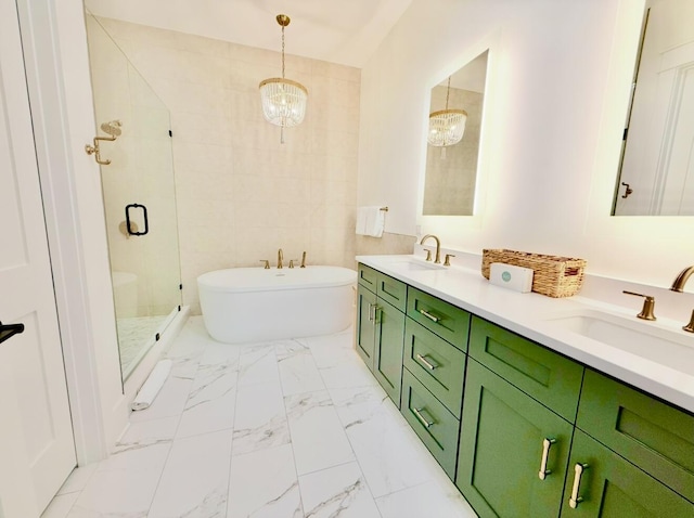 full bath with a stall shower, an inviting chandelier, a freestanding tub, marble finish floor, and a sink