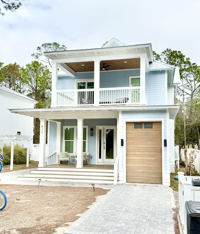 view of front facade with a porch, a balcony, decorative driveway, and a garage