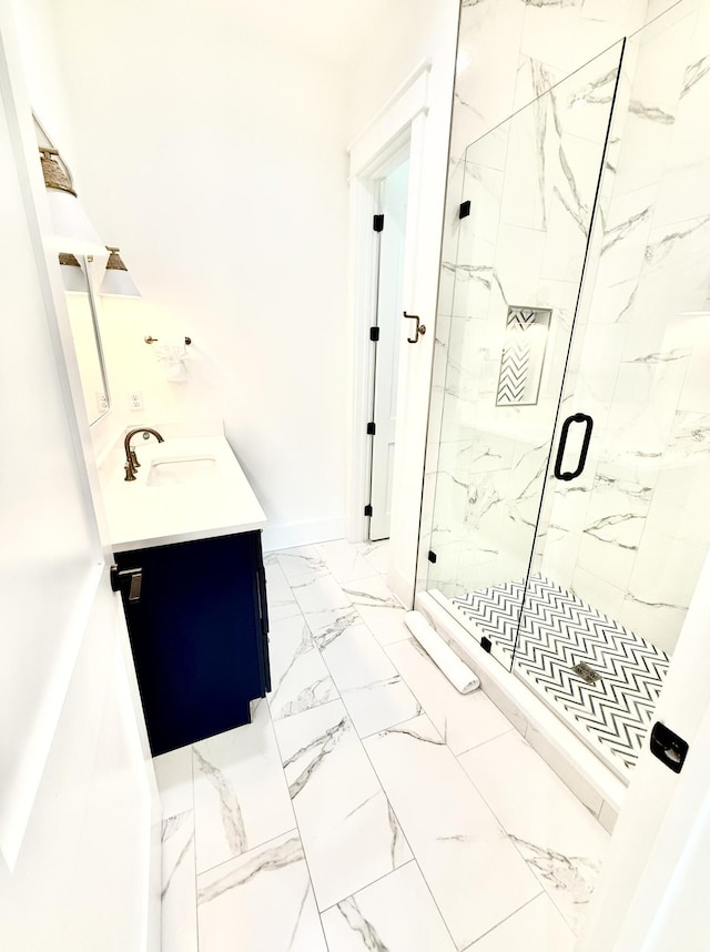 bathroom featuring vanity, baseboards, marble finish floor, and a marble finish shower