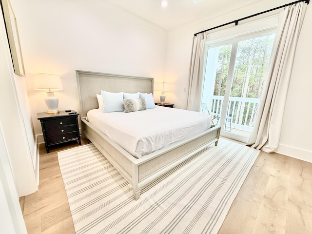 bedroom featuring baseboards, multiple windows, light wood-style floors, and access to outside