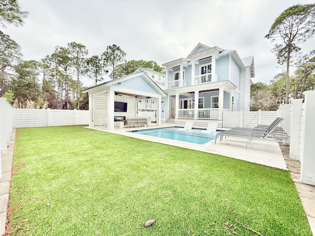 rear view of property with a balcony, a lawn, a patio, and a fenced backyard