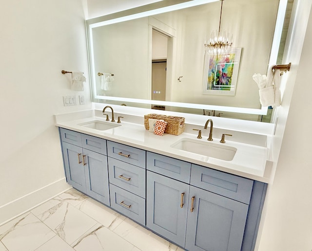 full bath with double vanity, baseboards, marble finish floor, and a sink