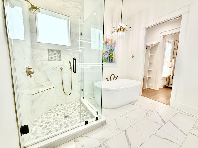 full bathroom featuring baseboards, a soaking tub, a stall shower, a notable chandelier, and marble finish floor