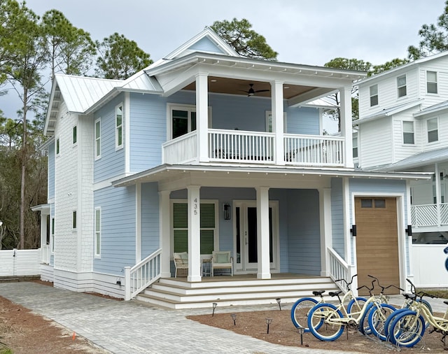 view of front of home with metal roof, a balcony, covered porch, and fence