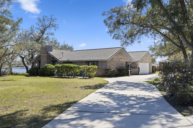 view of front of home featuring brick siding, a front lawn, a tiled roof, a garage, and driveway