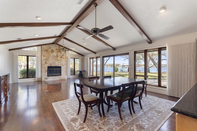 dining space with dark wood-type flooring, ceiling fan, vaulted ceiling with beams, and a textured ceiling