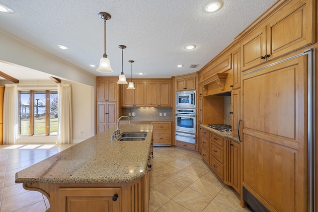 kitchen with a warming drawer, a center island with sink, a sink, backsplash, and built in appliances